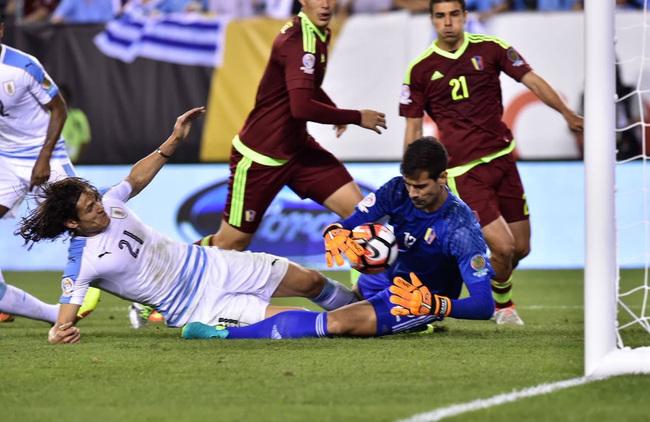 Edinson Cavani de Uruguay lucha con el portero venezolano Daniel Hernández.