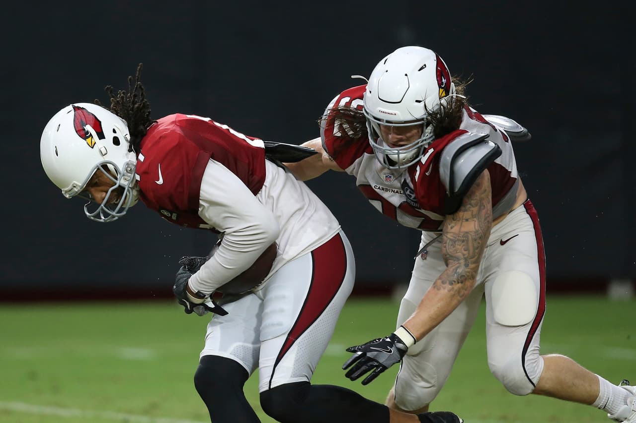 El receptor abierto de los Arizona Cardinals, Larry Fitzgerald (izquierda), atrapa el balón mientras su compañero linebacker, Dennis Gardeck (derecha), intenta la tacleada en el entrenamiento del equipo, en Glendale, Arizona.