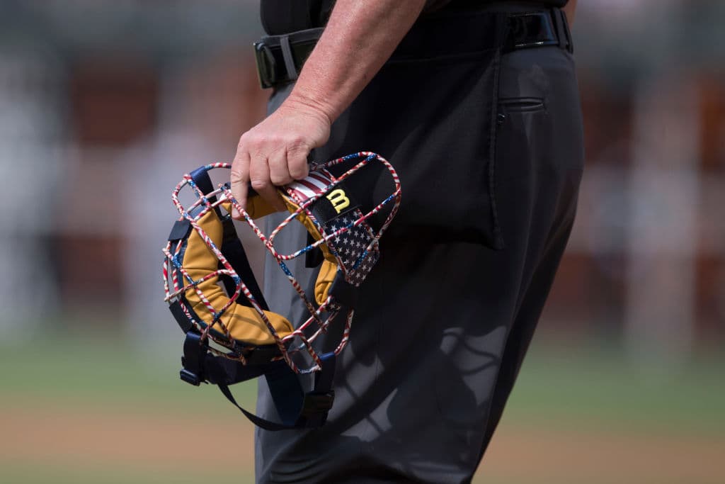 El umpire principal del juego entre los Baltimore Orioles y los Philadelphia Phillies en Citizens Bank Park sostiene su careta. Lucen los detalles patrióticos estadounidenses en su equipo de trabajo.