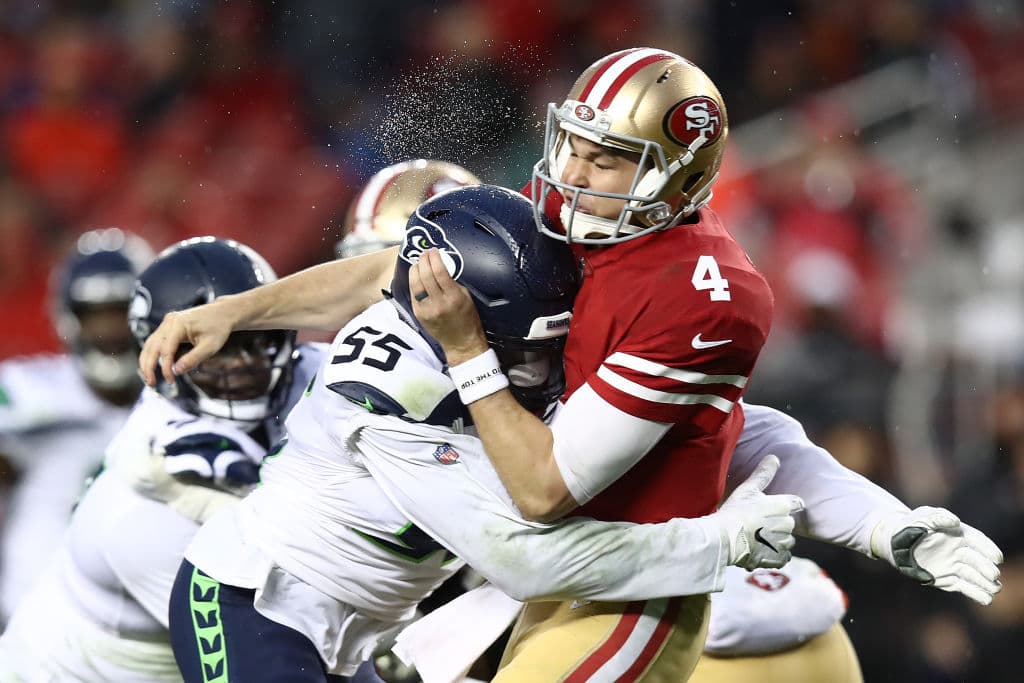 Nick Mullens (4) quarterback de los San Francisco 49ers, recibe un golpazo del linebacker Frank Clark (55) de los Seattle Seahawks durante su partido del domingo en Levi's Stadium.