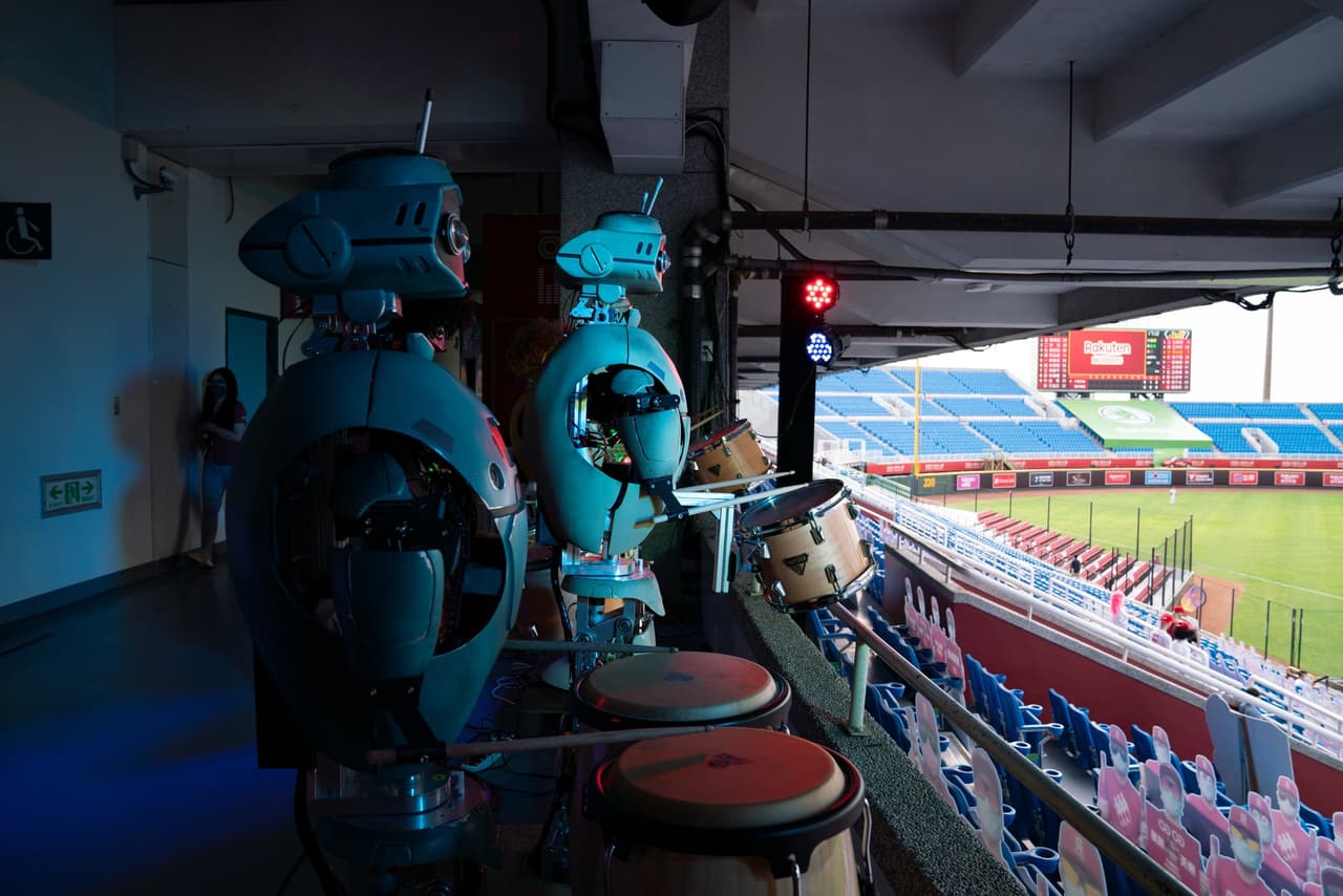 Una banda de robots tocan los tambores desde las alturas del estadio. Clarmente sutituyen a la música que se toca en vivo durante los partidos.