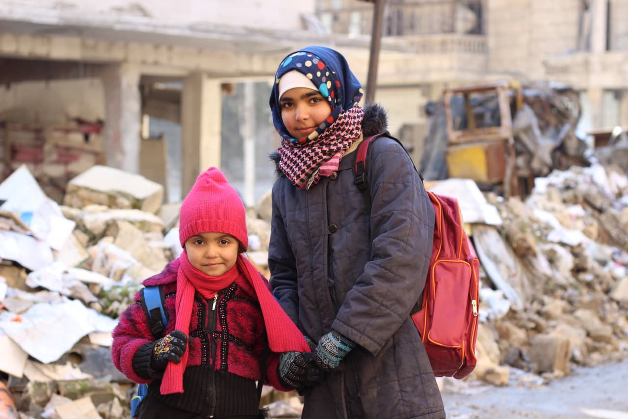 Seedra, de 6 años, y su hermana Baraa salen de clases el primer día del semestre en una escuela de Sakhoor, al este de Alepo, Siria. El tercer piso del edificio sufrió grandes daños durante por la guerra y sigue siendo inutilizable por lo que 600 niños son apretados en las aulas de los dos pisos restantes. Según cálculos de UNICEF, de 422 escuelas existentes al este de Alepo, 217 están destruidas, dañadas o inaccesibles. 30 de enero de 2017.