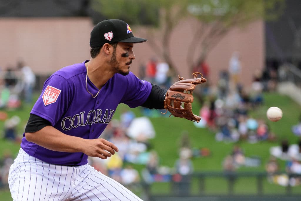Nolan Arenado de los Colorado Rockies fildea un rodado en el partido de entrenamiento primaveral en contra de los Oakland Athletics, una imagen estupenda, con la bola congelada y el guante abierto.
