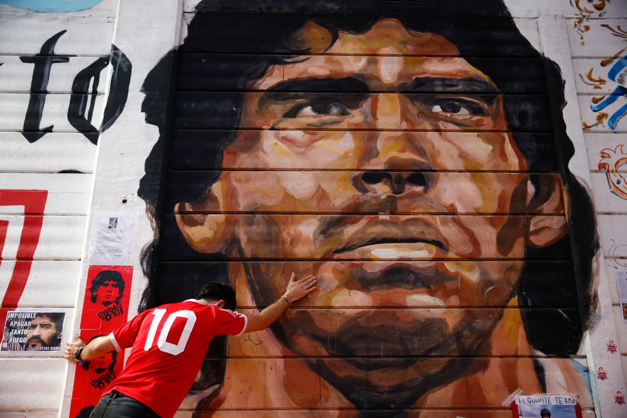 Un fanático con una camiseta con el 10 en la espalda toca un mural con el rostro de Maradona a las afueras del estadio de Argentinos Juniors, que lleva su nombre.