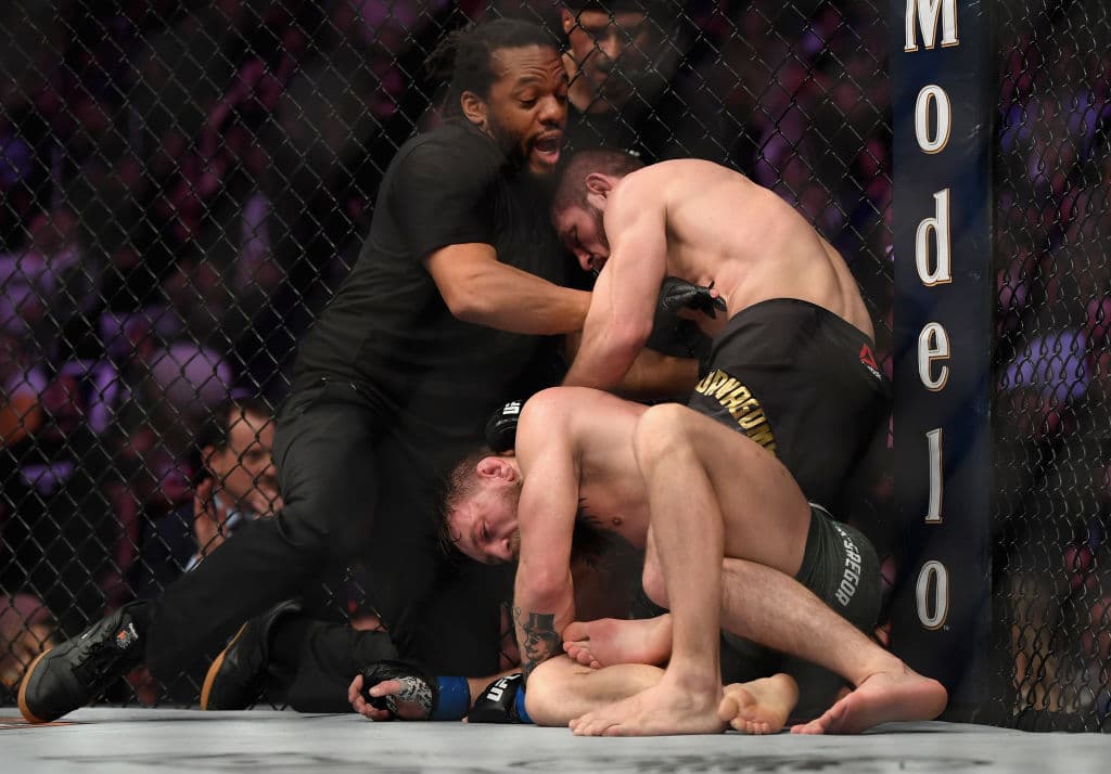 Eel árbitro Herb Dean (centro) separa a los peleadores tras la rendición de Conor McGregor (abajo) en el cuarto round.