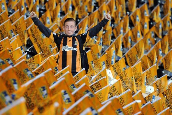 Aqui vemos una estampa del ambiente que se vive en los estadios. Un aficionado del Hull City sobresale entre los banderines de su equipo.