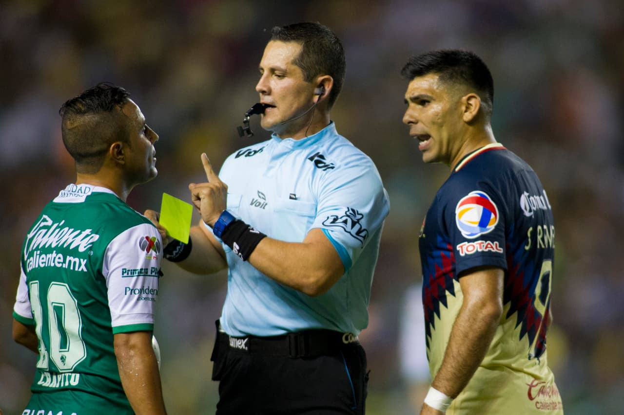 LEON, MEXICO - SEPTEMBER 27: Referee Diego Montano Robles shows the yellow card to Luis Montes of Leon and Silvio Romero of America during the 11th round match between Leon and America as part of the Torneo Apertura 2017 Liga MX at Leon Stadium on September 27, 2017 in Leon, Mexico. (Photo by Leopoldo Smith/Getty Images)