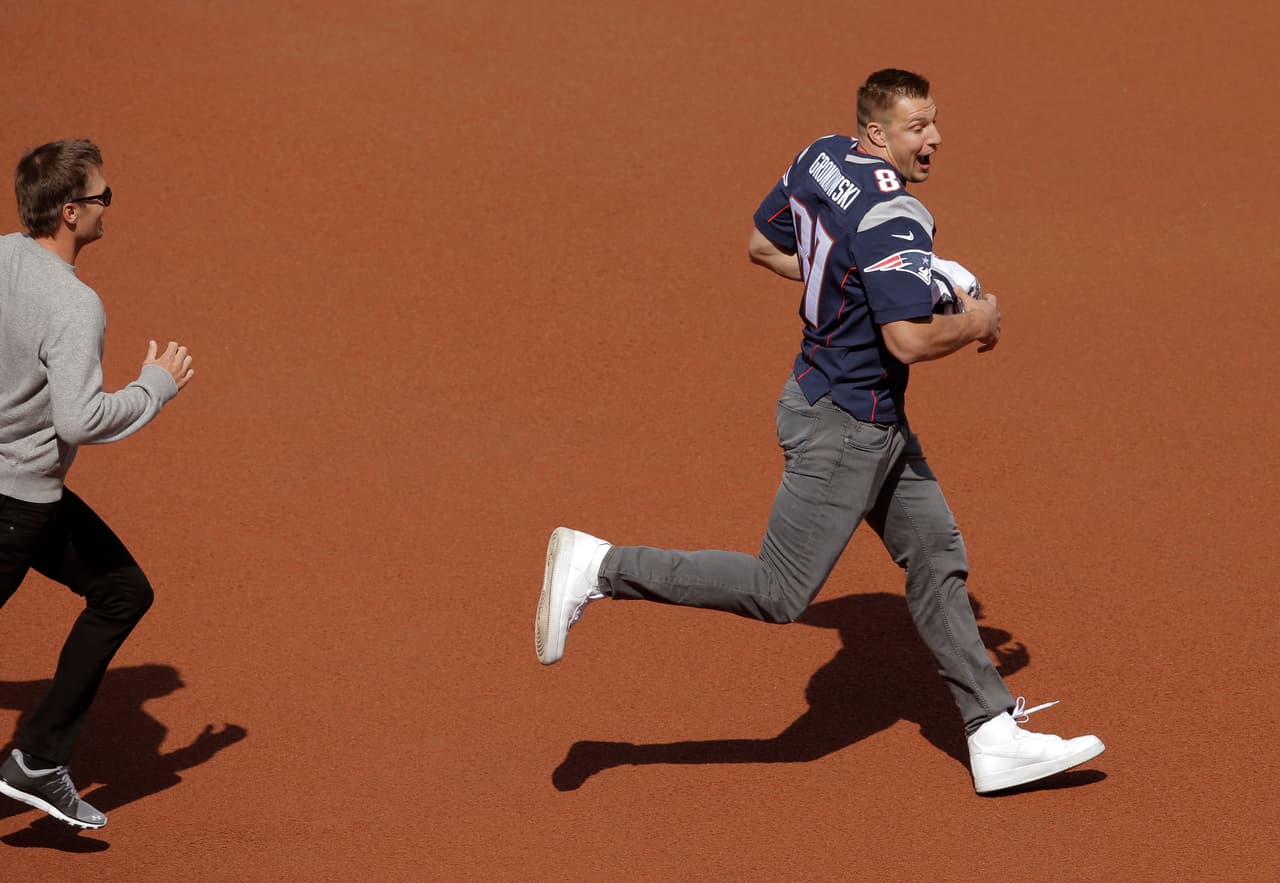 New England Patriots quarterback Tom Brady, left, chases tight End Rob Gronkowski, right, who had grabbed Brady's recovered jersey, which was stolen from the locker room after the Patriots' February Super Bowl victory over the Atlanta Falcons in Houston, during pregame ceremonies before a baseball game between the Boston Red Sox and the Pittsburgh Pirates on opening day at Fenway Park, Monday, April 3, 2017, in Boston. (AP Photo/Steven Senne)