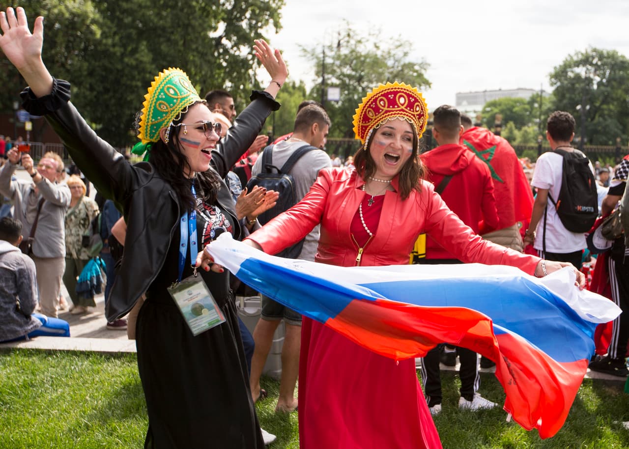 Two Russian national soccer team's fans dance with a Russian national flag near Red Square in Moscow, Russia, Thursday, June 14, 2018. Scalpers are still very visible at the World Cup, despite FIFA and Russia's claims they've cracked down on illicit ticket sales. (AP Photo/Alexander Zemlianichenko)