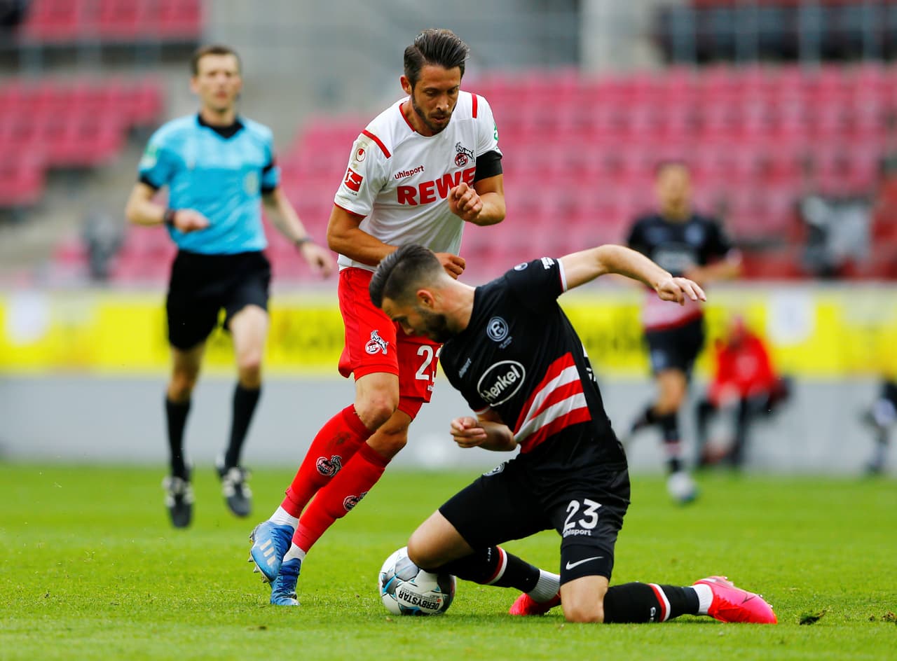 Giesselmann detiene el balón con la rodilla y evita el avance de Mark Uth.
