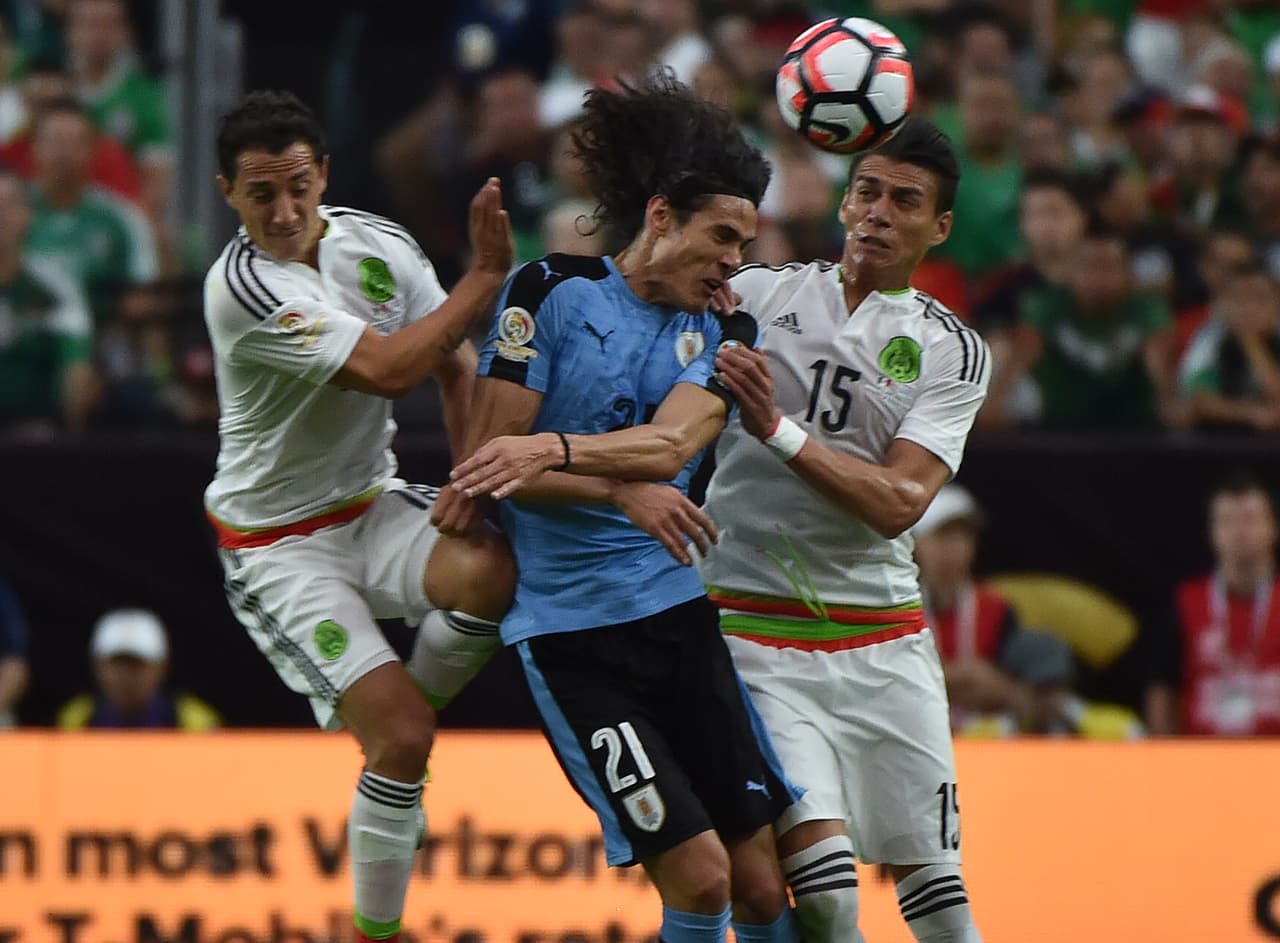 Edinson Cavani de Uruguay es marcado por Andrés Guardado y Héctor Moreno de México.