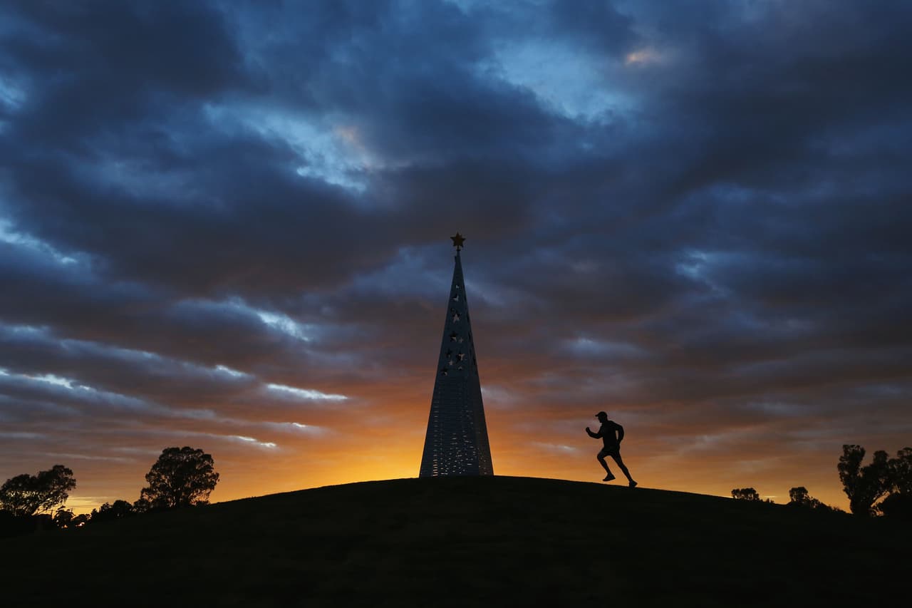 Un corredor realiza su mayor esfuerzo junto a un monumento en el Victoria Park Lake durante la Challenge Shepparton en esa ciudad de Australia, en un retrato durante la caída de la tarde.