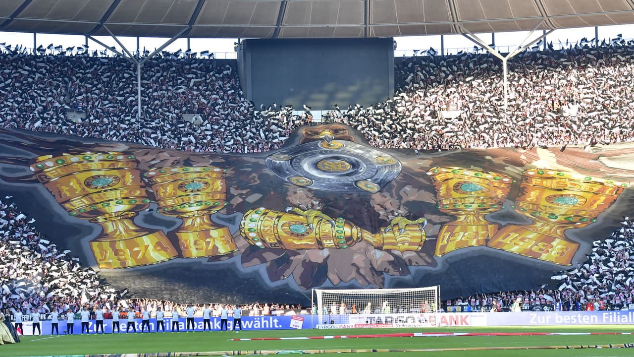 Fans cheer with banner featuring the trophy during the German Cup (DFB Pokal) final football match Eintracht Frankfurt v BVB Borussia Dortmund at the Olympic stadium in Berlin on May 27, 2017. / AFP PHOTO / John MACDOUGALL / RESTRICTIONS: ACCORDING TO DFB RULES IMAGE SEQUENCES TO SIMULATE VIDEO IS NOT ALLOWED DURING MATCH TIME. MOBILE (MMS) USE IS NOT ALLOWED DURING AND FOR FURTHER TWO HOURS AFTER THE MATCH. == RESTRICTED TO EDITORIAL USE == FOR MORE INFORMATION CONTACT DFB DIRECTLY AT +49 69 67880 / (Photo credit should read JOHN MACDOUGALL/AFP/Getty Images)