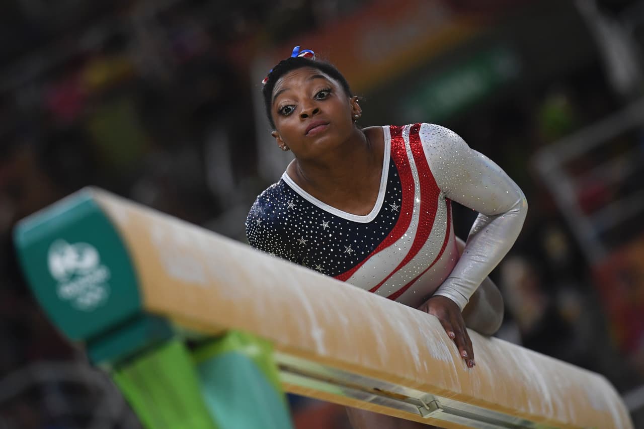 La atleta acostada sobre la barra de equilibrio, como parte del ejercicio en la final individual.