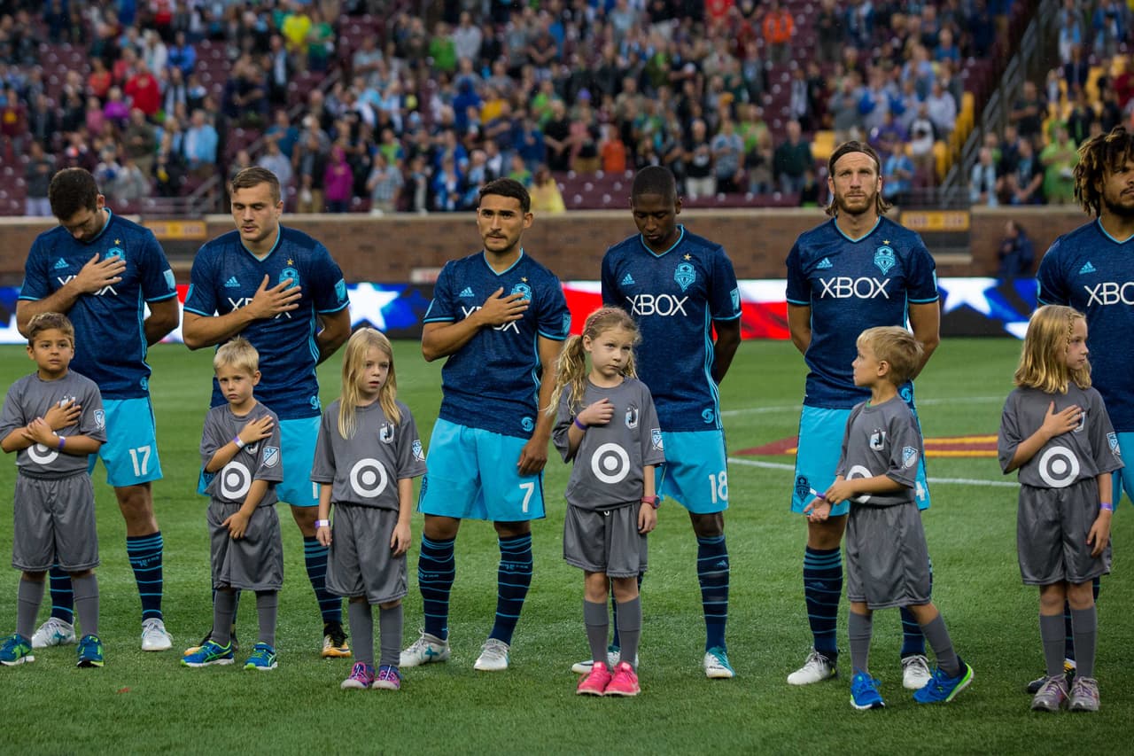 Jugadores de Seattle Sounders observan el himno nacional de EEUU.