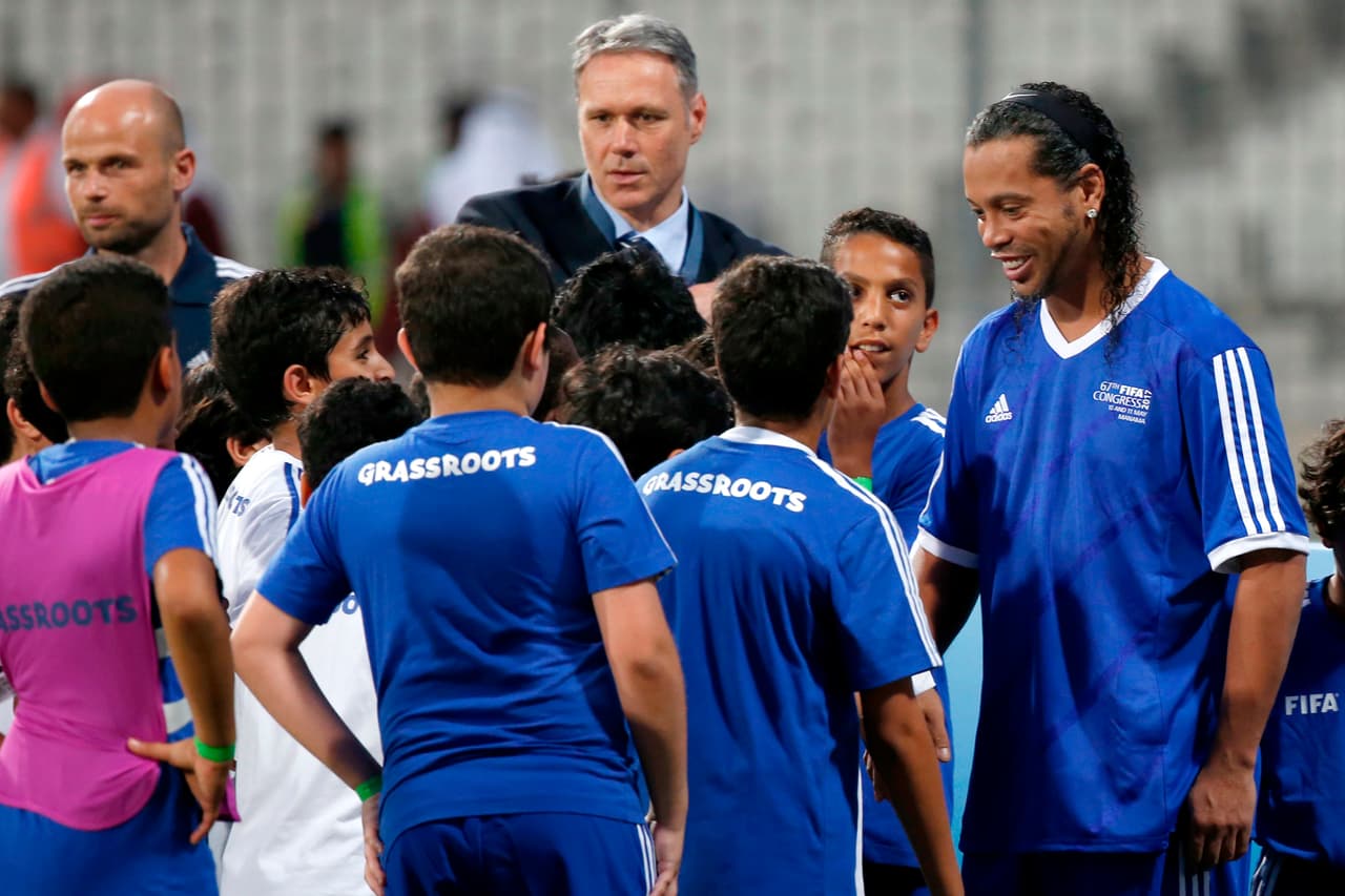 Retired Brazilian football player Ronaldinho (R) talks to child football players during the opening ceremony of a FIFA Legends football game on May 10, 2017 in Manama, Bahrain. / AFP PHOTO / JACK GUEZ (Photo credit should read JACK GUEZ/AFP/Getty Images)