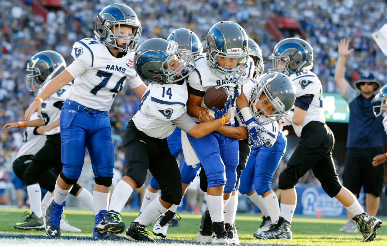 FILE- In this Aug 13, 2016, file photo, youngsters play in a pee-wee football game during halftime of a preseason NFL football game between the Los Angeles Rams and the Dallas Cowboys in Los Angeles. In the raging debate over the link between hard football hits and brain injuries, a slew of states have passed laws requiring players with concussions to sit out of games and get medical evaluations, but apparently only in one state, New York, has a lawmaker proposed taking the ultimate step, banning tackle football. (AP Photo/Ryan Kang, File)