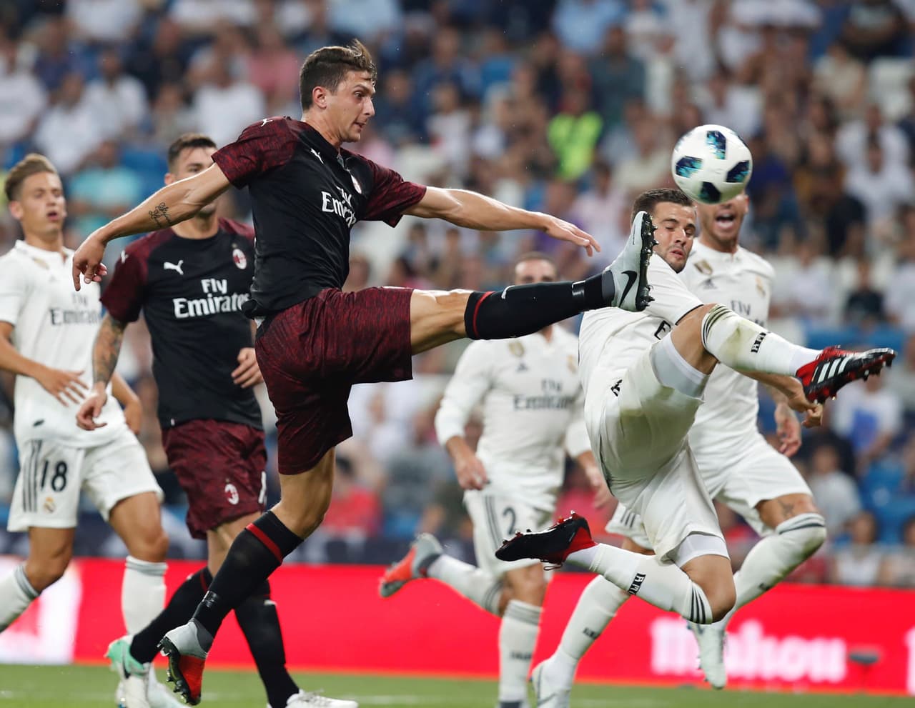 El defensa checo del Milan, Stefan Simic (izquierda), en disputa por el balón con Nacho Fernández (derecha) del Real Madrid.