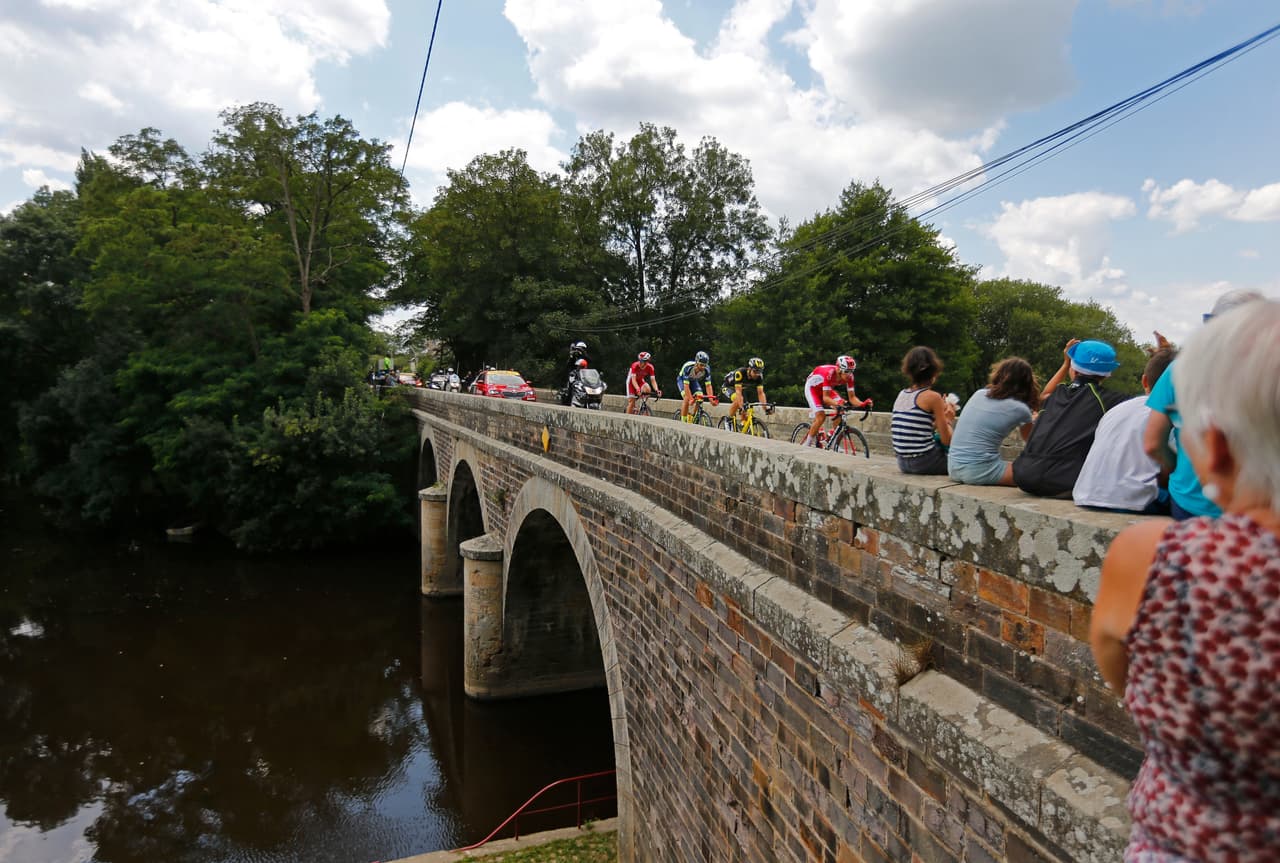 Una de las grandes bonanzas del Tour son las postales que regala esta prueba que en 2018 celebra su 115 aniversario. Aquí un grupo de ciclistas pasan por encima de un pintoresco puente.