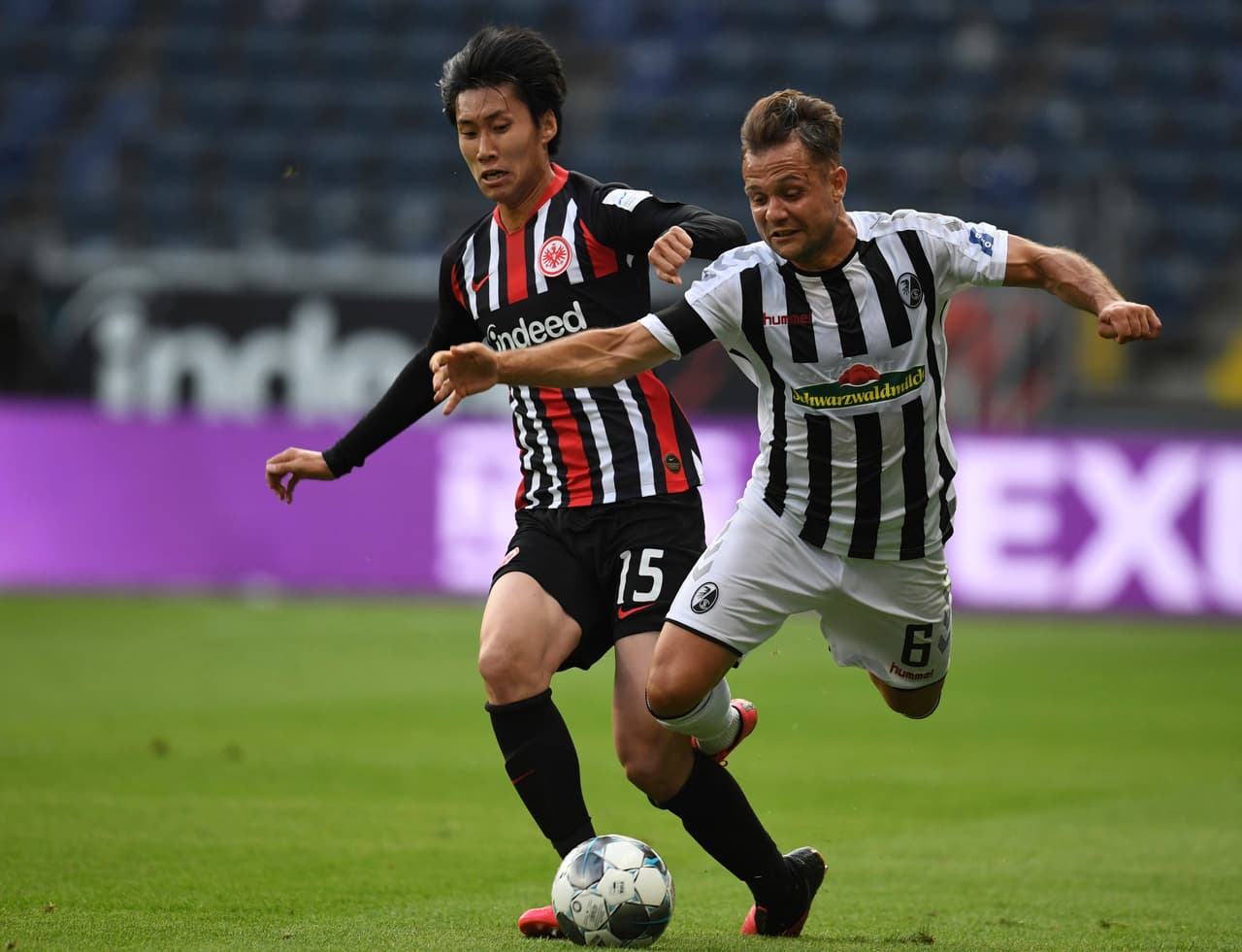 Daichi Kamada derriba accidentalmente al jugador del Freiburg Amir Abrashi.