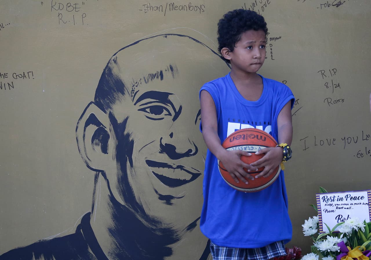 Un niño junto a un altar que fue improvisado en una cancha de baloncesto en Manila, Filipinas. Allí decenas de personas escribieron mensajes junto a un dibujo del rostro de Bryant. El helicóptero donde viajaba el astro de la NBA, su hija y otras siete personas, cayó en la ladera de una colina en medio de una densa niebla matutina, unas 25 millas al oeste de Los Ángeles.