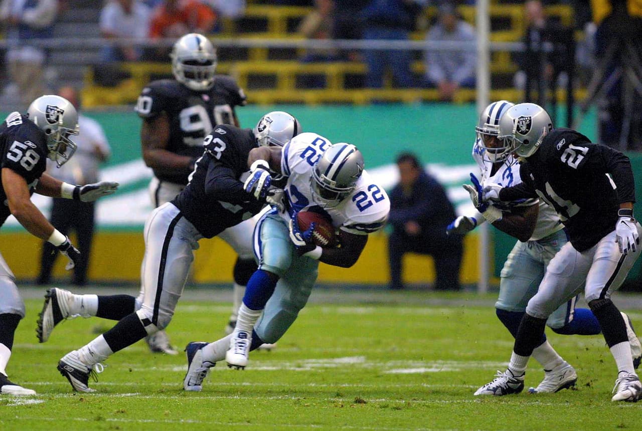 El corredor de Dallas, Emmitt Smith, es tacleado por el profundo Marquez Pope de los Raiders durante el segundo cuarto del American Bowl 2001 disputado en el Coloso de Santa Úrsula.