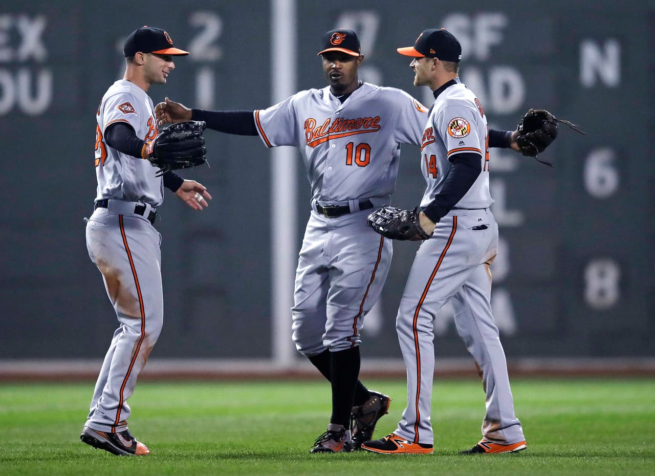 El jardinero de los Orioles, Adam Jones, centro, festeja con sus compañeros Craig Gentry, derecha, y Joey Rickard, tras vencer a los Medias Rojas el lunes, 1 de mayo de 2017, en Boston. (AP Photo/Charles Krupa)