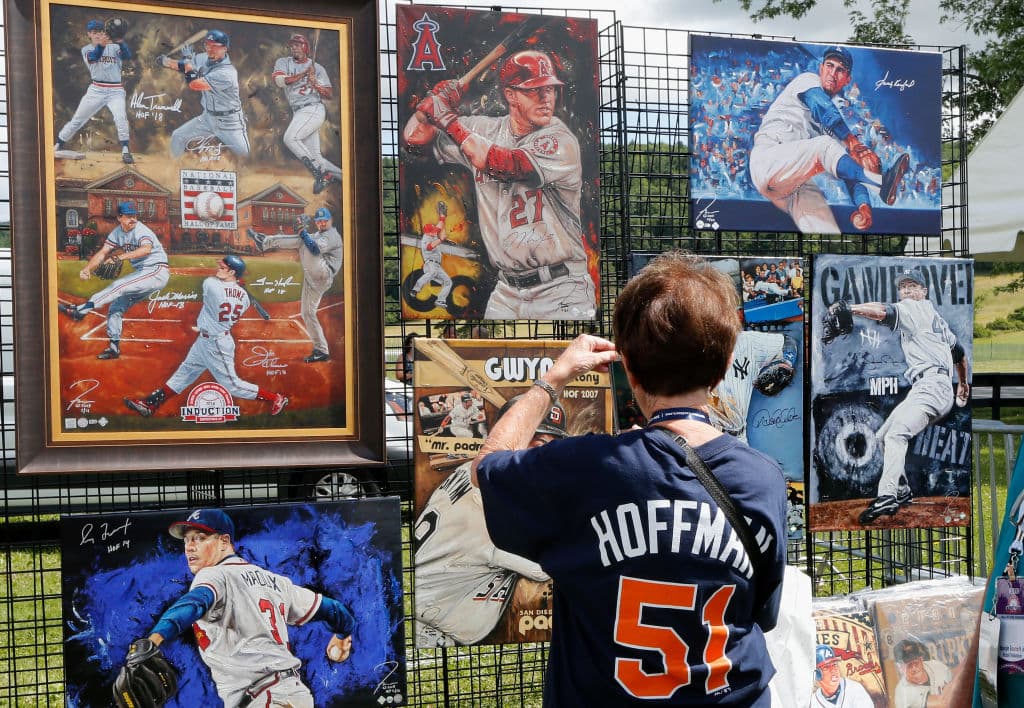 Un fanático observa ilustraciones de jugadores históricos de las Grandes Ligas en espera de la ceremonia de inducción al Salón de la Fama del béisbol en Cooperstown, Nueva York.