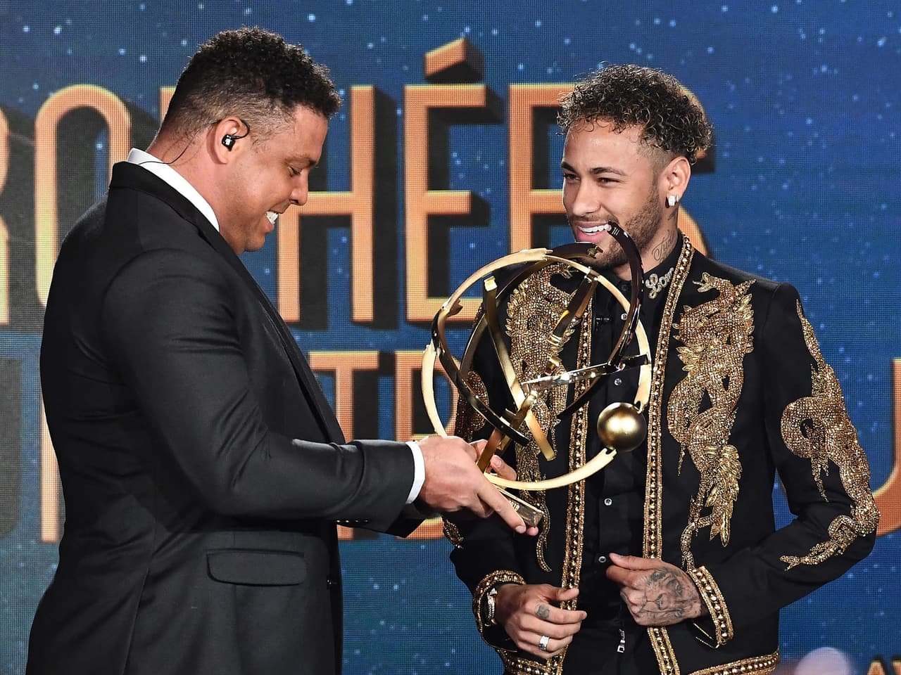 Paris Saint-Germain's Brazilian forward Neymar (R) smiles after receiving the Best Ligue 1 Player award from former Brazilian international player Ronaldo during a TV show on May 13, 2018 in Paris, as part of the 27th edition of the UNFP (French National Professional Football players Union) trophy ceremony. / AFP PHOTO / FRANCK FIFE