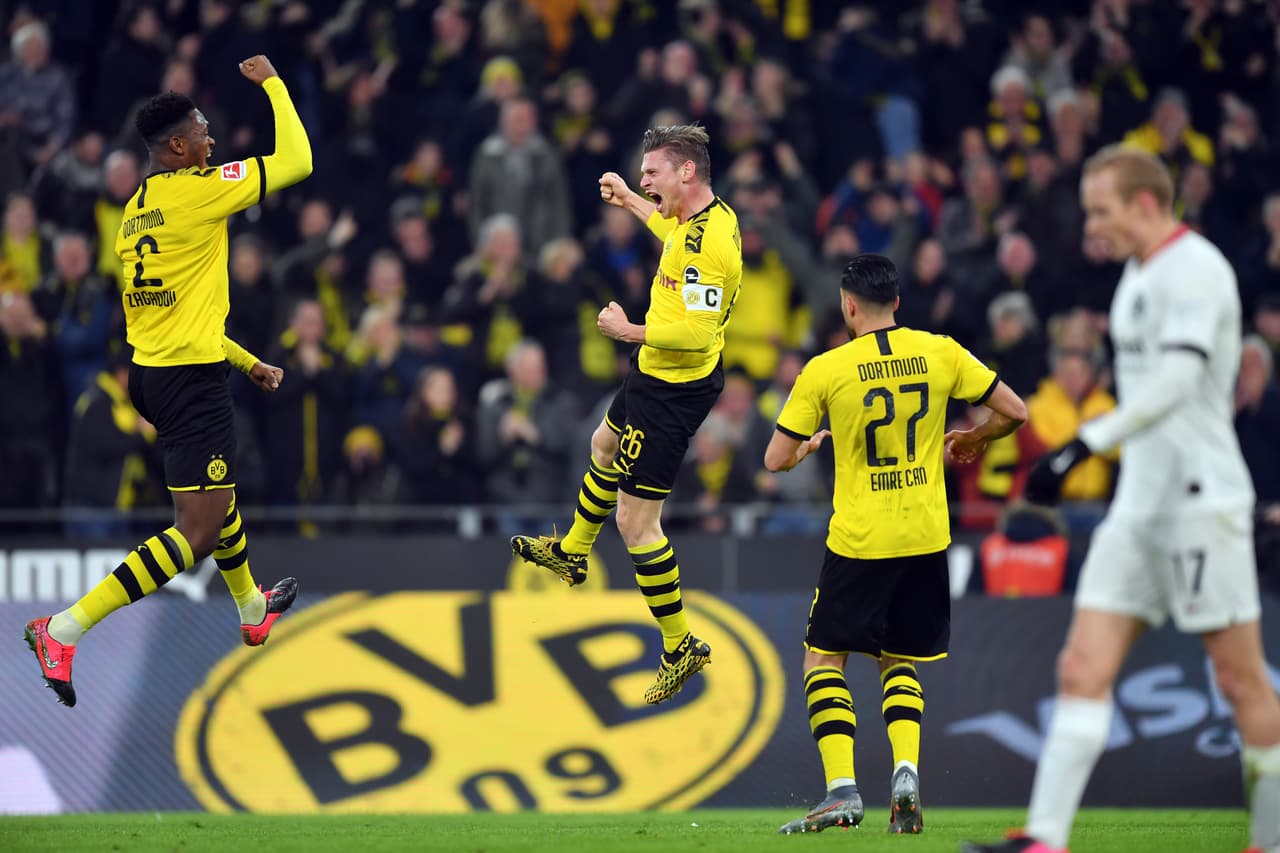 Lukas Piszczek del Borussia Dortmund celebra con Dan-Axel Zagadou y Emre Can ante el lamento del arquero del Frankfurt. Borussia llegó a 42 puntos y está a cuatro del líder Bayern Múnich.