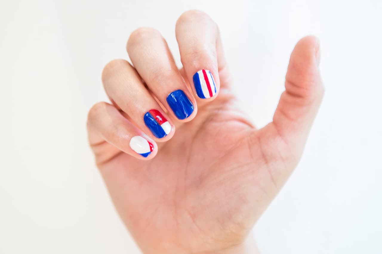 Costa Rica: Aplica 2 capas de esmalte blanco en la uña del dedo meñique e índice y 2 en tono azul en la del dedo medio y sólo la mitad del anular (de manera vertical). Con la ayuda de un pincel más delgado pinta la parte superior de la uña del anular en rojo y azul el resto. En la del dedo meñique haz un francés en V con barniz azul y rojo. Traza dos líneas verticales azules y una roja en la uña del dedo índice.