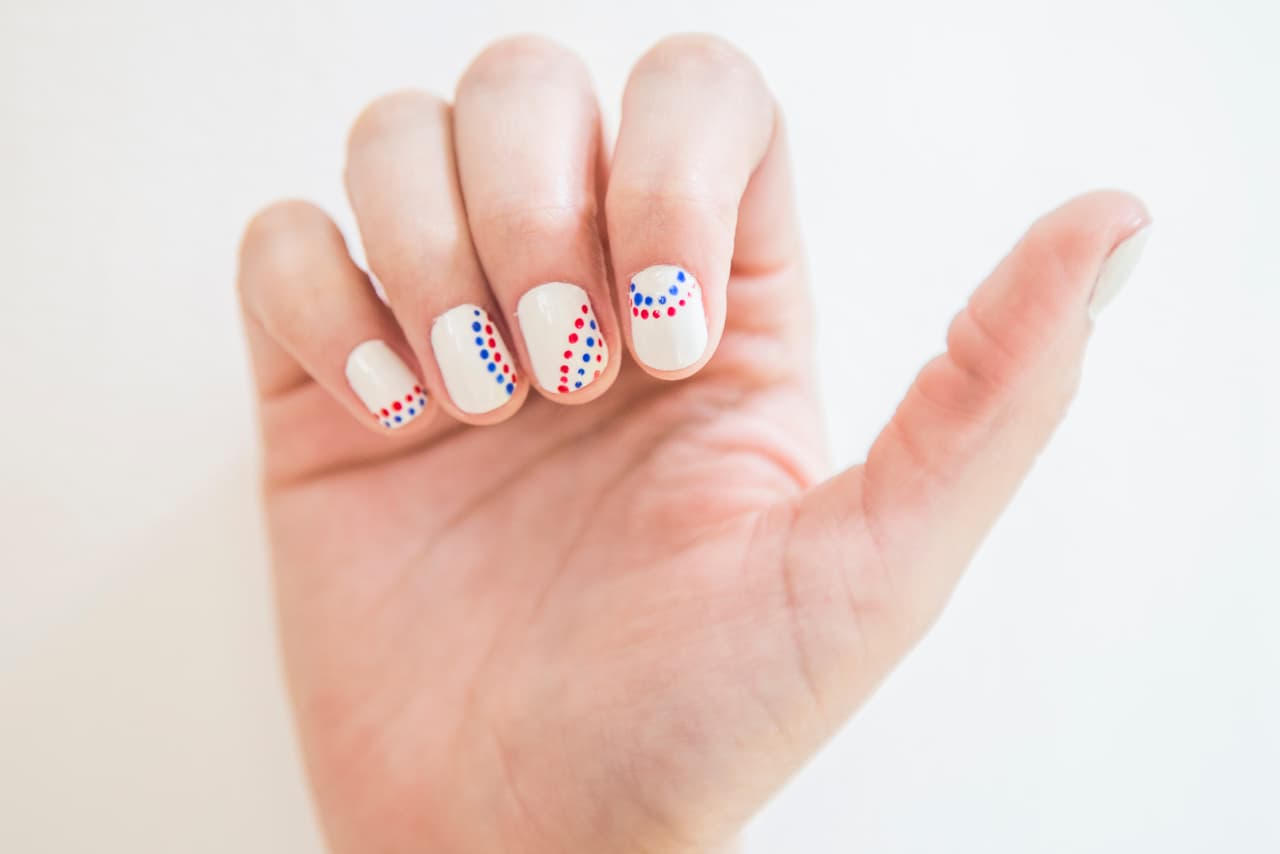Paraguay: Da 2 capas de esmalte blanco en todas las uñas. Con un punzón marca puntos rojos y azules, ¡ponte creativa y haz un diseño distinto en cada uña!
