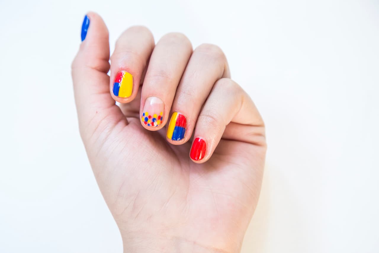Ecuador: Aplica 2 capas de esmalte rojo en la uña del dedo meñique y 2 en tono azul en la uña del dedo pulgar. Pinta la mitad del índice y del anular de amarillo, rellena la mitad superior de esmalte rojo y la inferior de azul. Con ayuda de un punzón pinta puntos amarillos, rojos y azules. Es importante que se sequen completamente antes de que utilices un color diferente.
