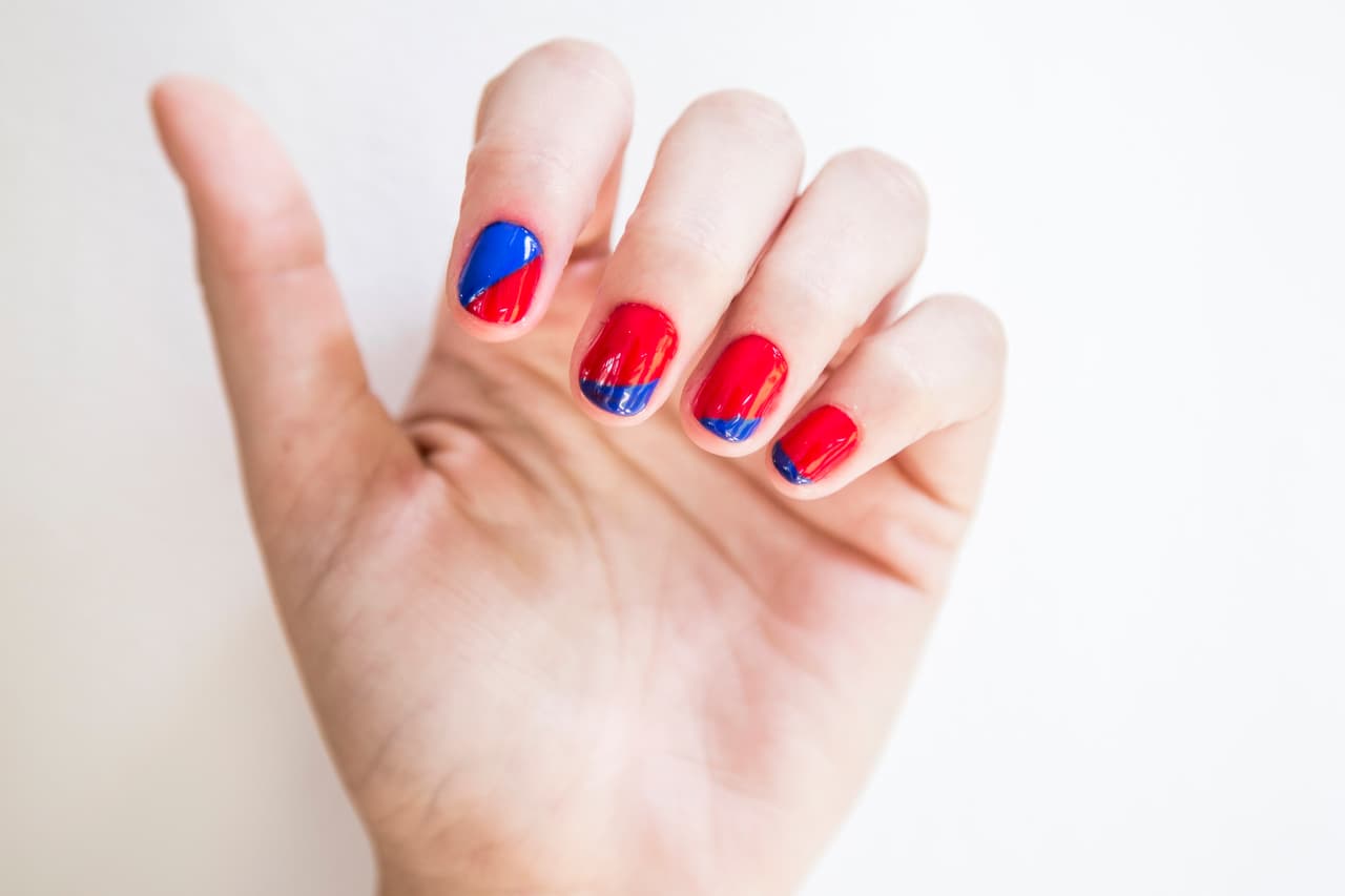 Haití: Aplica 2 capas de esmalte azul sólo en la mitad de la uña del dedo índice y dos capas en tono rojo en el resto de las uñas. Haz un francés con la brocha del esmalte azul en la uña del dedo meñique, en el anular pinta sólo la esquina y en el dedo medio un triángulo que abarque toda la orilla de la uña. Rellena la mitad que no está pintada con esmalte rojo.