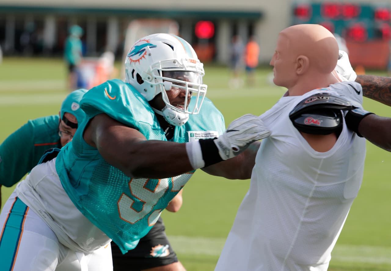 Dándole con todo a un 'dummy' de tacleo aparece el tacle defensivo de los Miami Dolphins Akeem Spence en uno de los ejercicios del día en el entrenamiento del equipo.