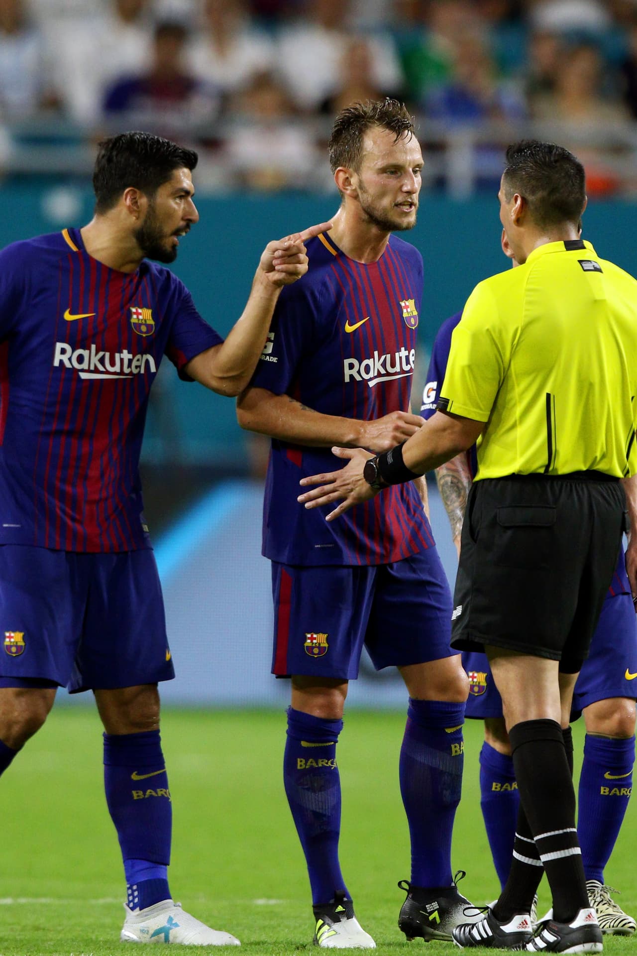 MIAMI GARDENS, FL - JULY 29: Barcelona midfielder Ivan Rakitic (4) and forward Luis Suárez (9) confront referee Jair Marrufo about a foul during the second half of the International Champions Cup match at Hard Rock Stadium in Miami Gardens, FL. Barcelona defeated Real Madrid 3-2. (Photo by Douglas Jones/Icon Sportswire via Getty Images)