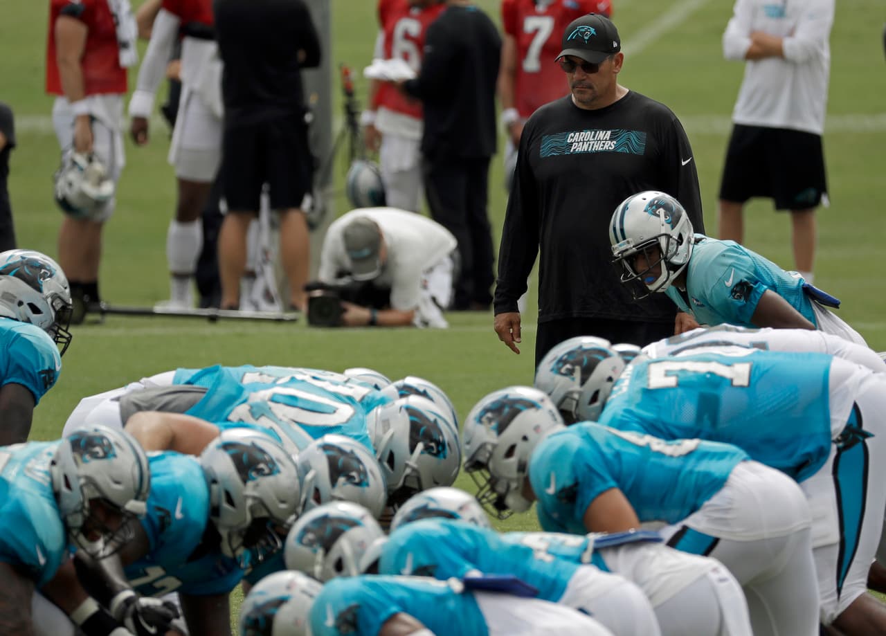 Al fondo, de pie y con atuendo negro, se aprecia Ron Rivera, el entrenador principal de las Panteras de Carolina, quien atentamente observa el desempeño de sus jugadores en el entrenamiento.