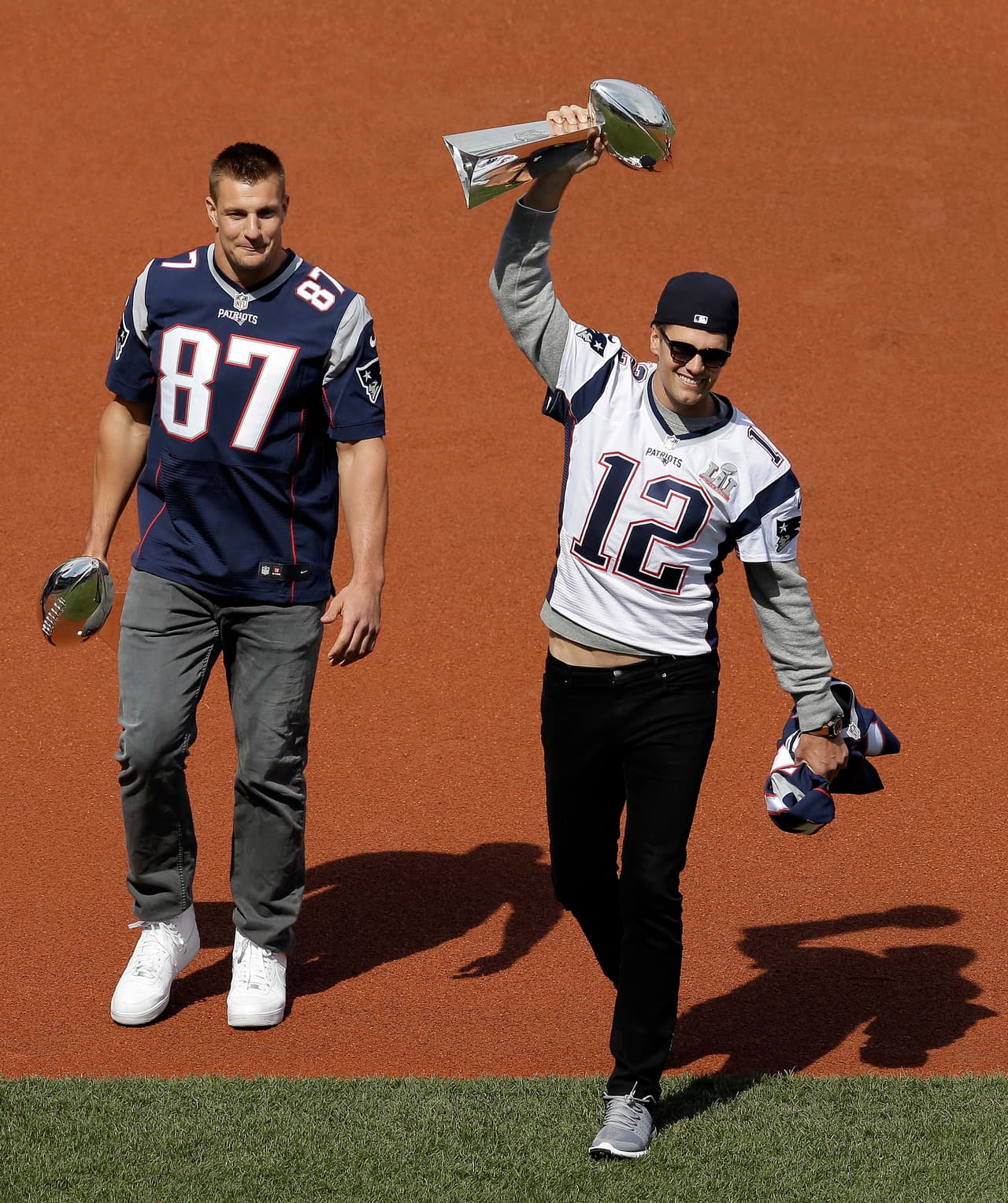 New England Patriots quarterback Tom Brady, right, displays one of the team's Super Bowl trophies as tight End Rob Gronkowski, left, carries another during pregame ceremonies before a baseball game between the Boston Red Sox and the Pittsburgh Pirates on opening day at Fenway Park, Monday, April 3, 2017, in Boston. (AP Photo/Steven Senne)