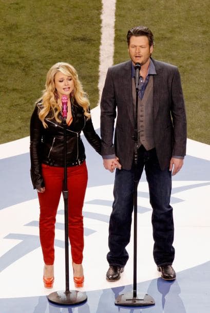 Miranda Lambert y Blake Shelton tomados de la mano en medio de la cancha.