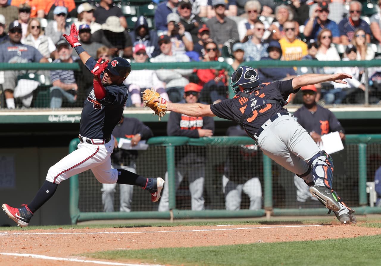¡Espectacular imagen! Andrés Blanco de los Atlanta Braves elude el toque del receptor de los Detroit Tigers John Hicks (55) para anotar una carrera en su partido de pretemporada de este día.