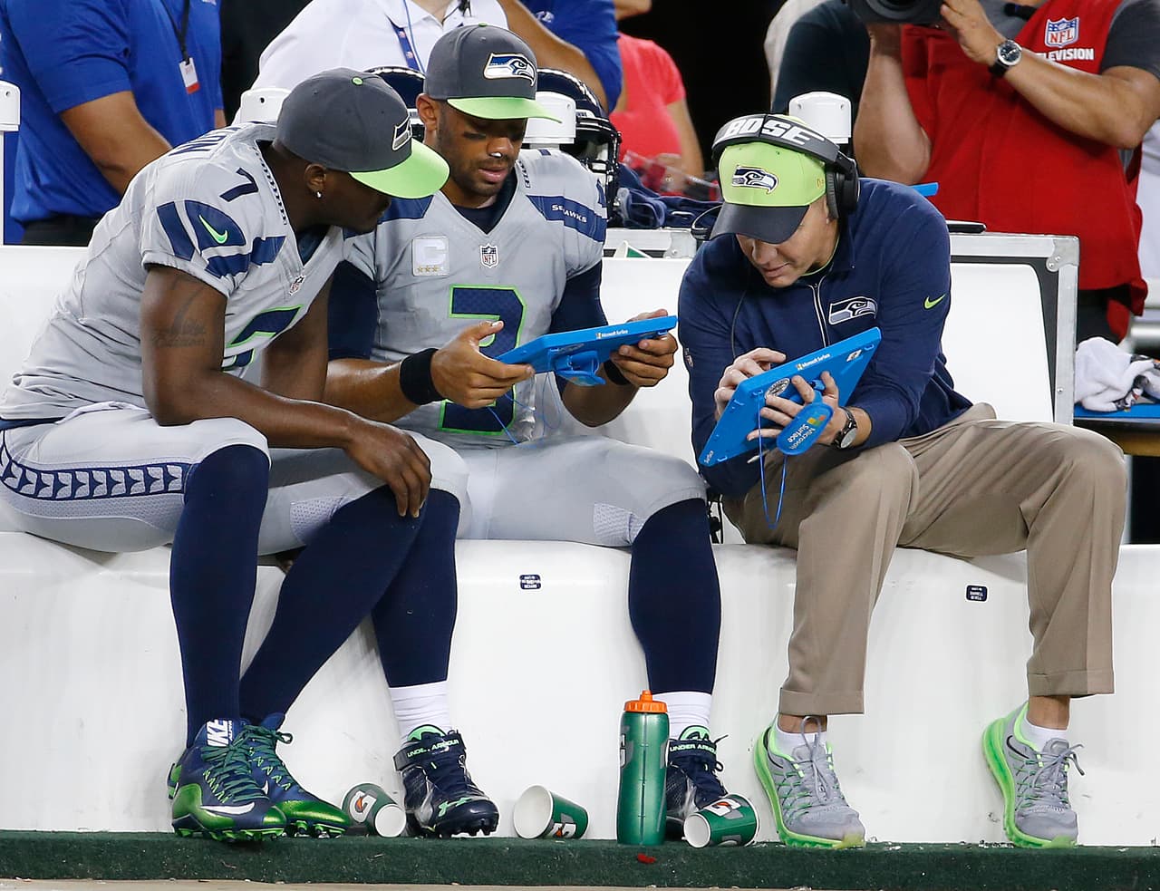Seattle Seahawks quarterbacks Tavaris Jackson (7) and Russell Wilson (3) and offensive coordinator Darrell Bevell look at a Microsoft Surface tablets on the sideline during an NFL game against the San Francisco 49ers at Levi's Stadium on October 22, 2015. The Seahawks defeated the 49ers 20-3. (Kevin Terrell via AP)