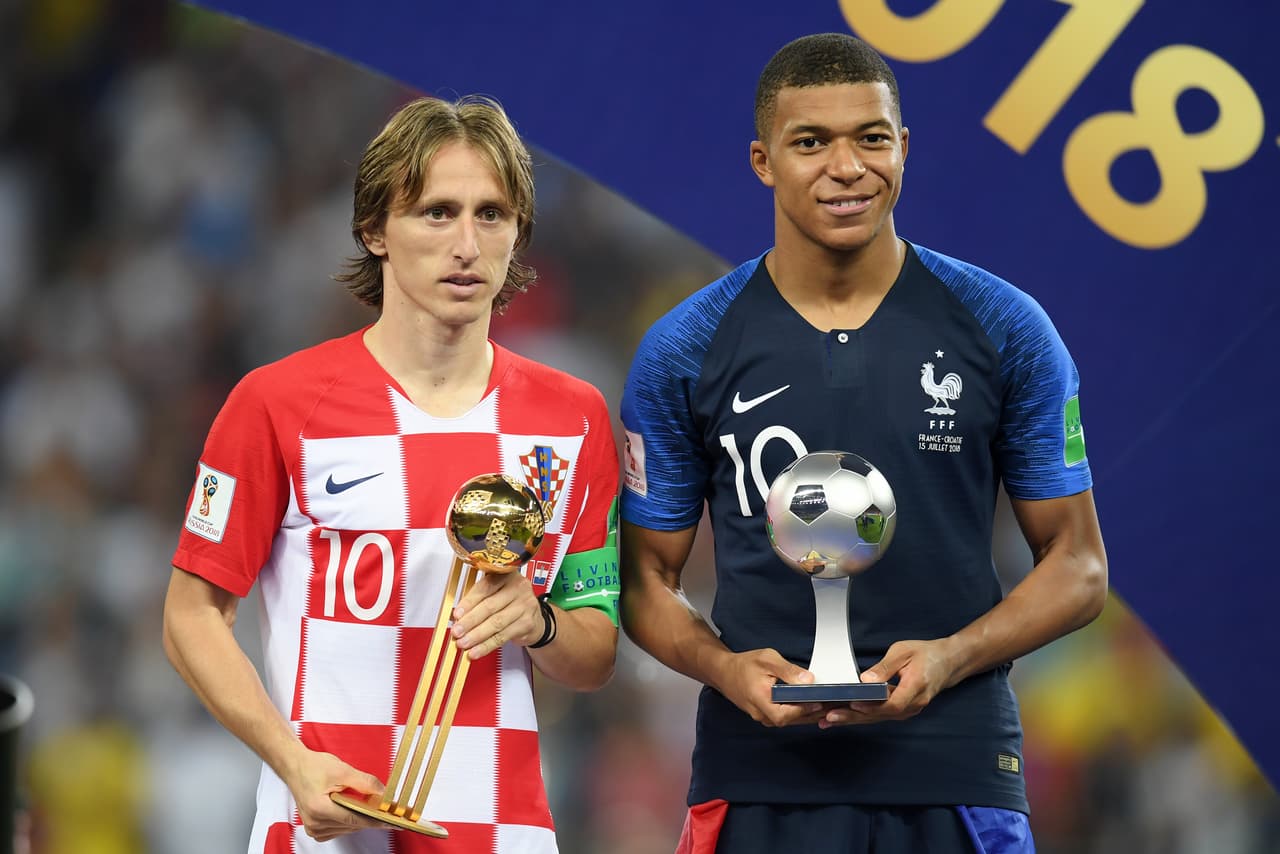 Esta es otra de las imágenes de la final del Mundial. El croata Luka Modric posa (apesadumbrado tras perder la final) con el Balón de Oro que le reconoce como el jugador más valioso del Mundial, mientras que el francés Kylian Mbappé, de solo 19 años, sostiene el título al mejor jugador joven. Los dos futbolistas dicen mucho de lo que representan sus selecciones. En el caso de Modric, tuvo que abandonar su pueblo natal de niño cuando asesinaron a su abuelo en medio de la guerra de los balcanes y fue descubierto en un campo de refugiados.
