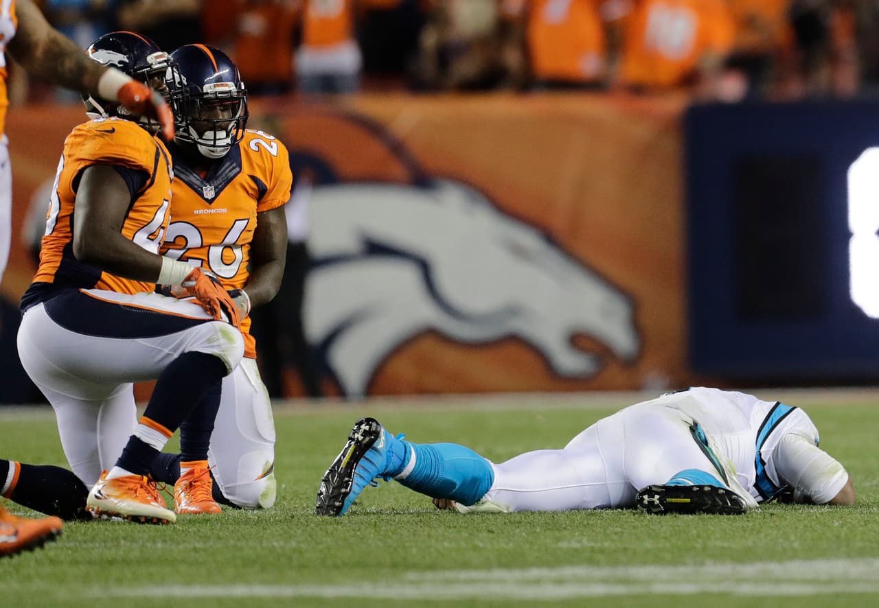 Cam Newton, quarterback de los Panthers de Carolina, yace en el césped tras recibir un golpe de Darian Stewart (26), de los Broncos de Denver, el jueves 8 de septiembre de 2016 (AP Foto/Joe Mahoney)