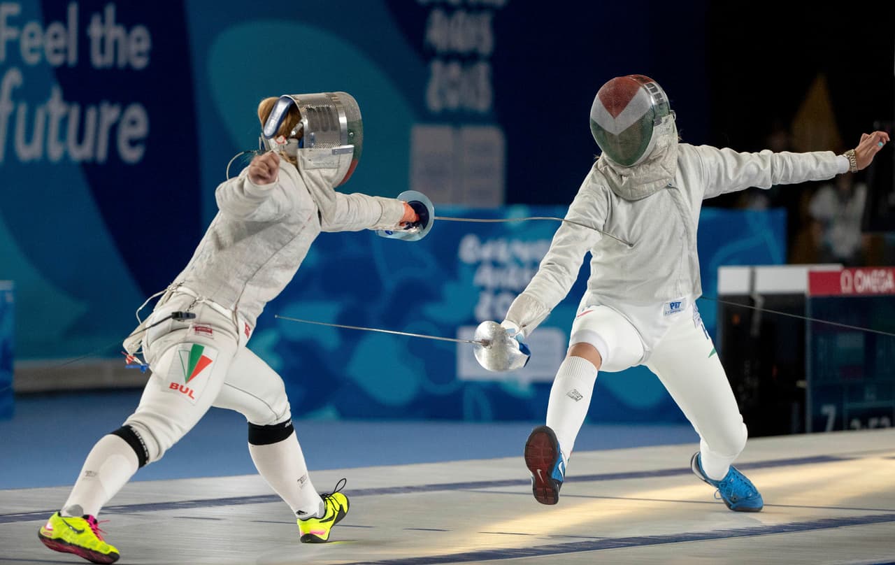 Yoana Ilieva de Bulgaria (izq) se mide ante la húngara Liza Pusztai en la competencia de equipos mixtos continentales en el Pabellón África para cerrar la participación en la esgrima.