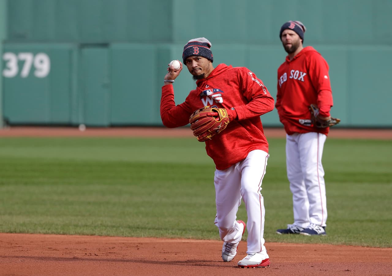 Ante la mirada de Dustin Pedroia al fondo, Mookie Betts hace un tiro a la inicial en la práctica de fildeo del equipo esta mañana.