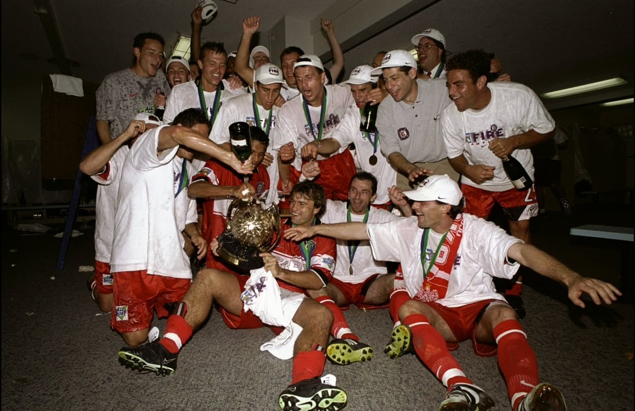 Los jugadores de Chicago Fire, campeones en 1998, prueban que el trofeo Alan I. Rothenberg es una auténtica copa.