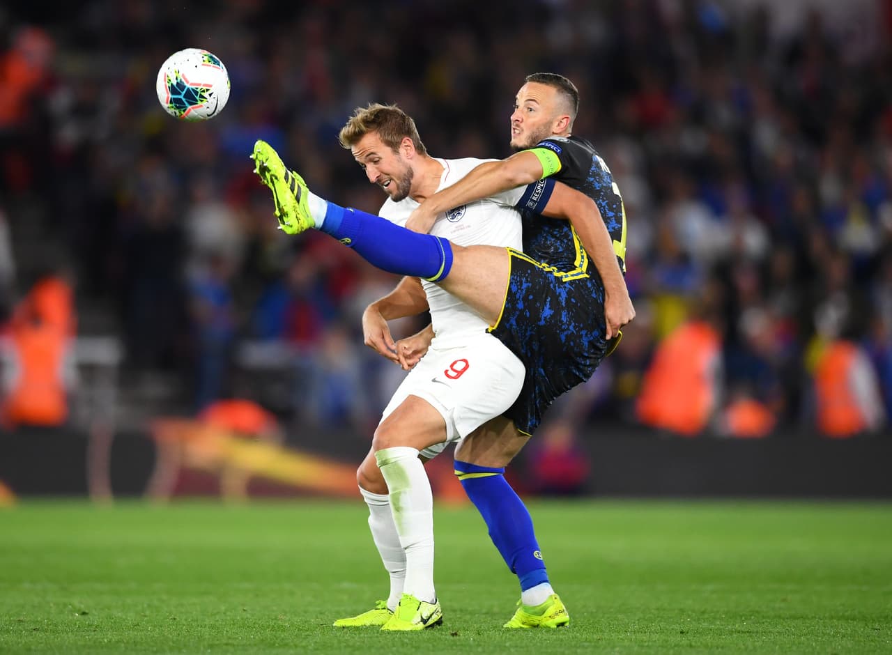 Amir Rrahmani lucha con Kane por un balón en el aire, el defensor de Kosovo se salecon la suya.