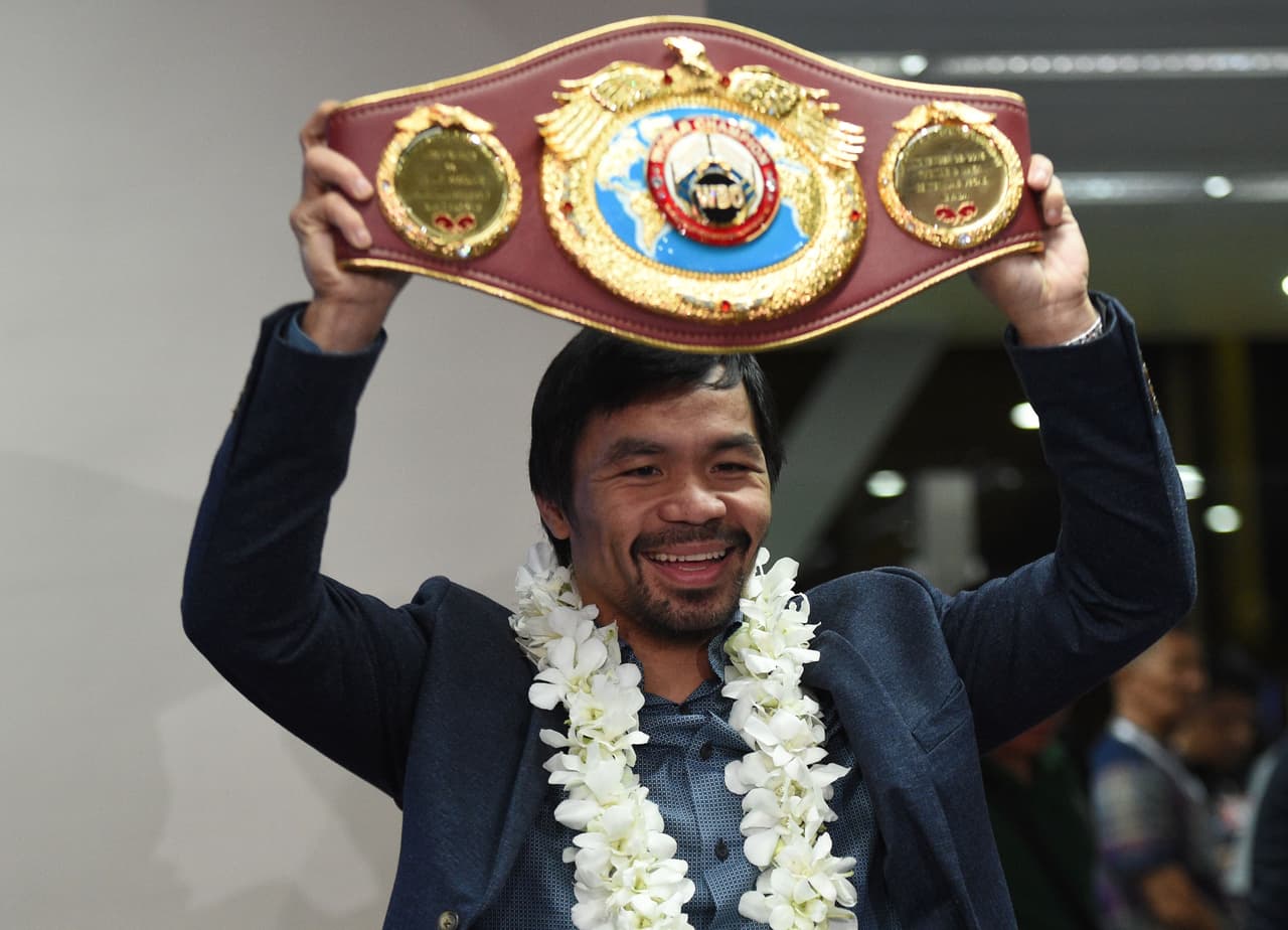 Philippine boxing icon Manny Pacquiao holds his welterweight title belt upon arriving at Manila airport on November 8, 2016, days after reclaiming the World Boxing Organization welterweight title for the third time with a unanimous decision victory over former champion Jesse Vargas of Mexico. / AFP / TED ALJIBE (Photo credit should read TED ALJIBE/AFP/Getty Images)