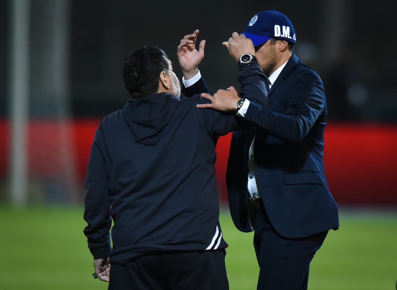 Maradona felicita a Alexander Medina, entrenador de Talleres, y le obsequia su gorra.