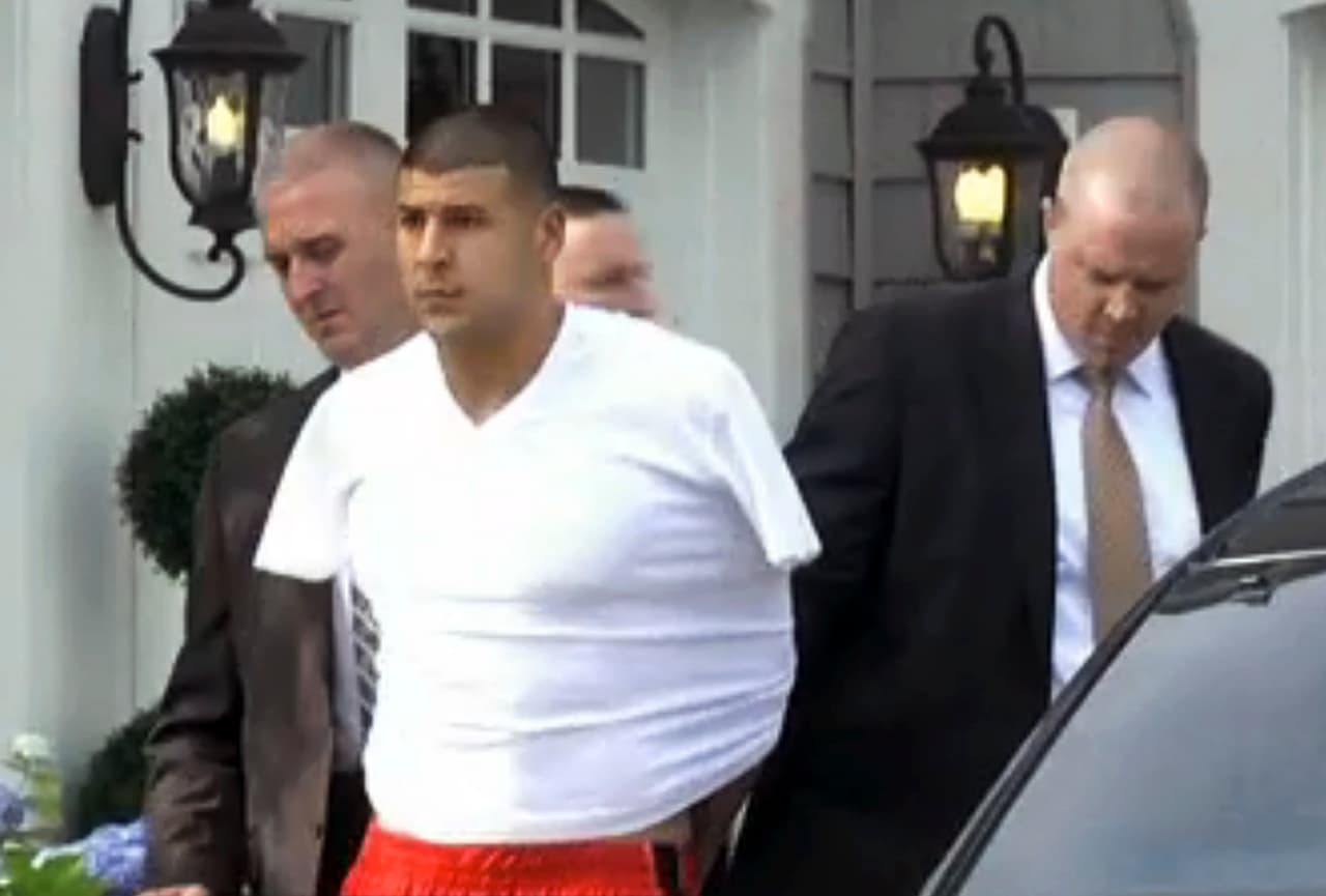 In this image taken from video, police escort Aaron Hernandez from his home in handcuffs in Attleboro, Mass., Wednesday, June 26, 2013. Hernandez was taken from his home more than a week after a Boston semi-pro football player was found dead in an industrial park a mile from Hernandez's house. (AP Photo/ESPN)